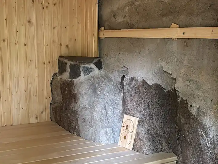 The sauna's rock wall and thermometer
